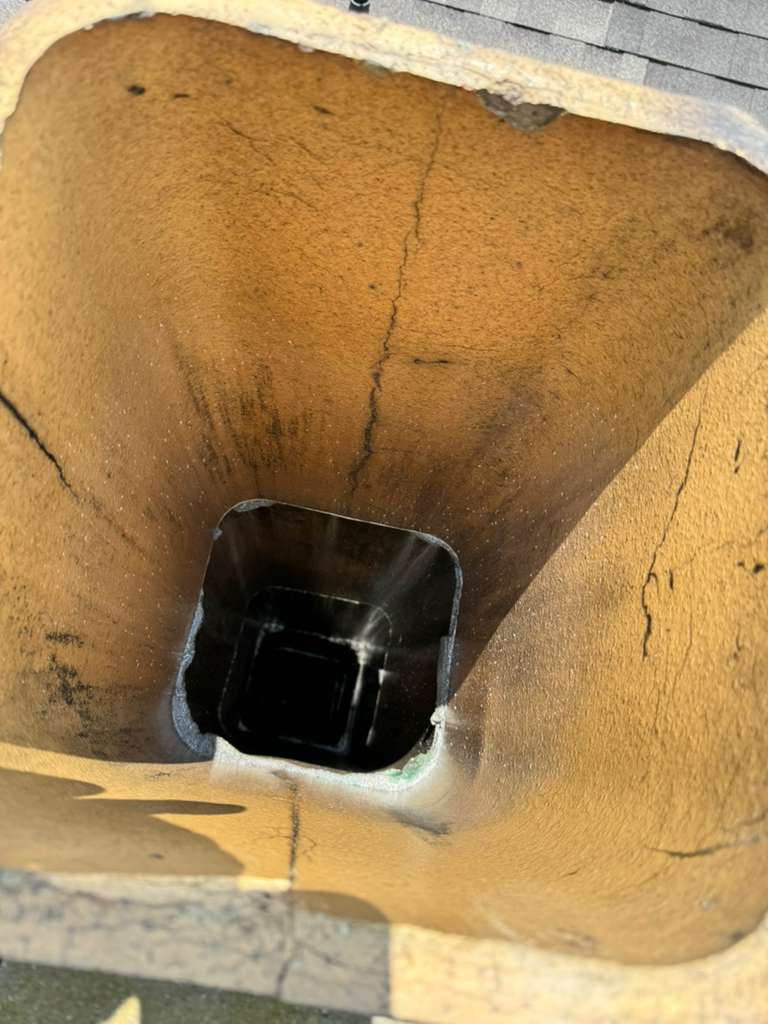 Chimney flue interior before ceramic coating, showing cracked and worn liner