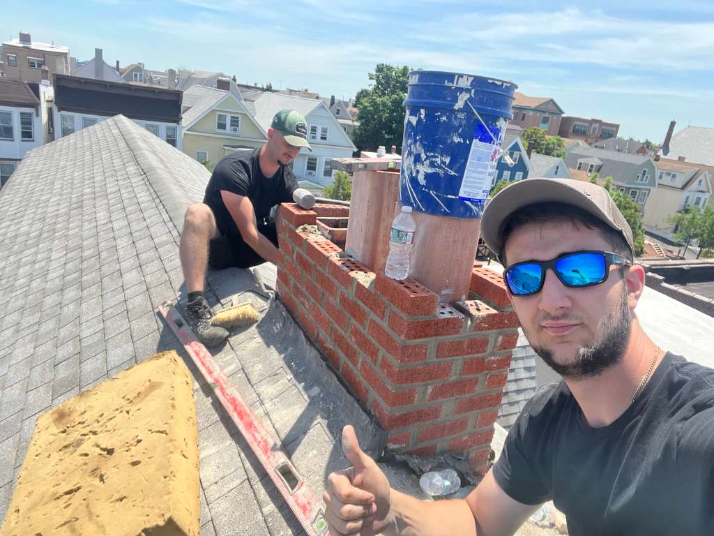 Brother's Bond crew on a residential roof repairing a red brick chimney